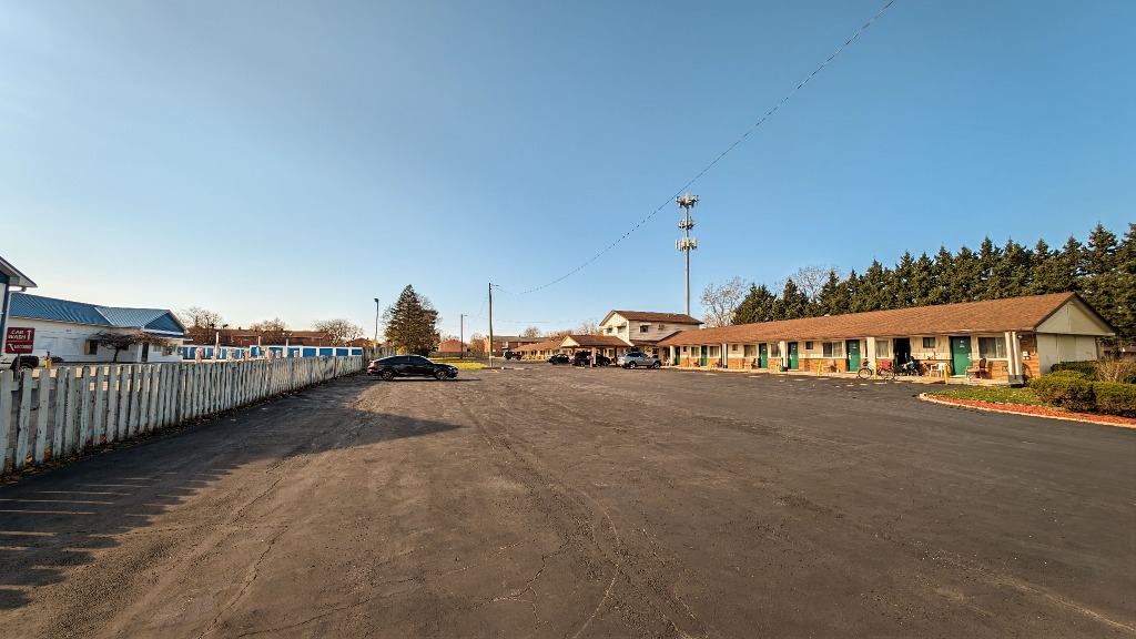 Delta Motel exterior wide view with spacious paved parking lot and clear blue sky